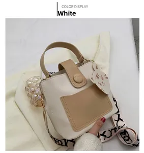 Detail of color-block PU leather bag featuring a cute cat charm and wide graphic strap