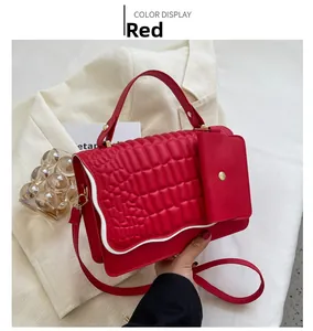 Detail of red crossbody bag with crocodile texture, gold hardware, and small pouch