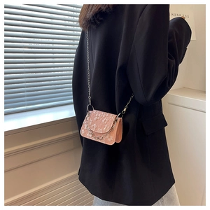 Detail of pink jacquard mini crossbody bag with silver chain on model in black blazer