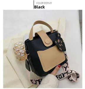 Detail of black crossbody bag with cat charm and stylish wide patterned shoulder strap