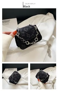 Macro detail of black floral jacquard fabric and silver four-leaf clover chain strap