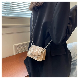 Detail of beige lace embroidery crossbody bag with floral accents and silver chain