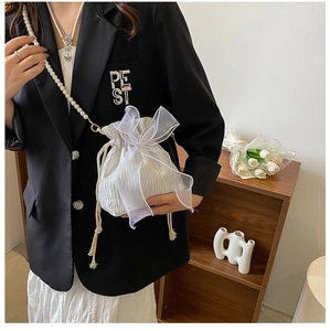 Detail of white drawstring bucket bag with large organza bow and pearl chain strap