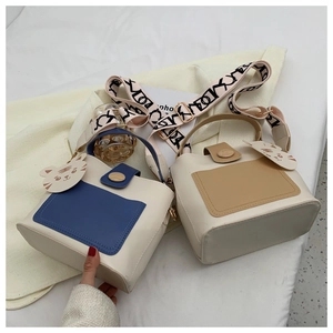 Detail of contrast color tote bag with tiger charm and patterned wide shoulder strap