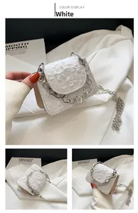 Detail view of white mini shoulder bag featuring 3D floral texture and silver chain strap