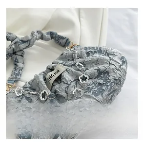 Détail de la chaîne florale argentée et texture plissée du sac nuage pour femme