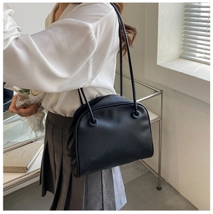 Detail view of black leather shoulder bag showing delicate thin straps and hardware