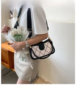 Detail of quilted beige shoulder bag with black trim and woven handle on model