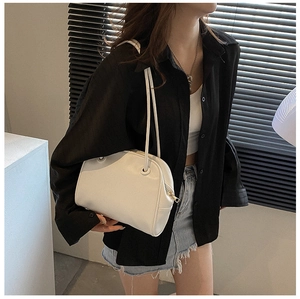 Model wearing a white minimalist leather underarm bag with gold zipper and dual straps