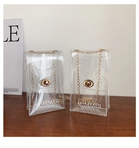 Close-up of clear PVC mini crossbody bags with gold chains and SUMMER text on wooden table