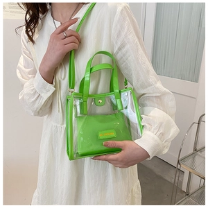 Detail of neon green transparent PVC tote bag with inner zipper pouch on a white dress