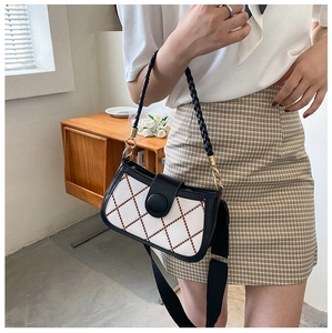 Close-up of white quilted crossbody bag with red stitching and wide fabric shoulder strap
