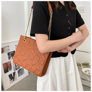 Détail du sac cabas matelassé marron avec chaîne dorée et coutures géométriques
