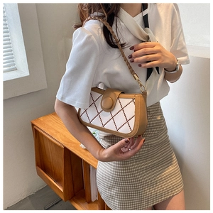 Detail of white quilted handbag with red diamond pattern and woven shoulder strap