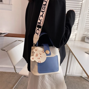 Fashionable cream and blue bucket bag with a wide patterned strap and a tiger charm