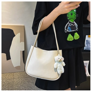 Détail d'un sac à bandoulière crème avec un adorable pendentif en forme d'ours blanc