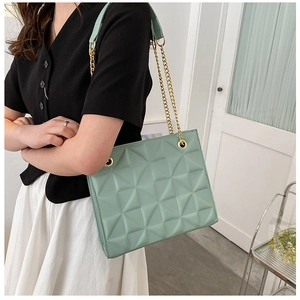 Détail d'un sac bandoulière matelassé vert menthe avec chaîne dorée sur mannequin