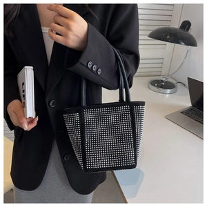 Close-up of black matte tote bag with silver metal rivets and leather top handles