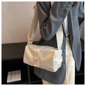 Close-up of white nylon crossbody toast bag with wide strap and plastic buckle detail