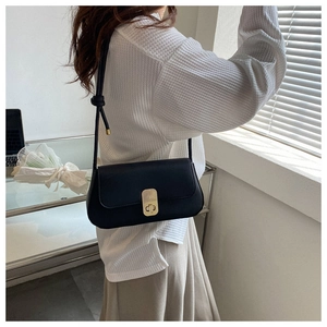 Detail of black pebbled leather handbag featuring a vertical textured gold metal clasp