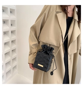 Close-up of black quilted bucket bag with gold chain strap and drawstring closure