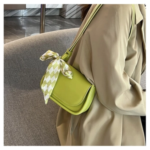 Dettaglio della borsa a tracolla in pelle verde con elegante foulard di seta a quadretti