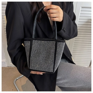 Detail of a black rhinestone bucket bag showing sparkling silver crystals and leather handle