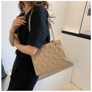 Détail du sac à bandoulière matelassé beige avec chaîne dorée sur tenue en tweed
