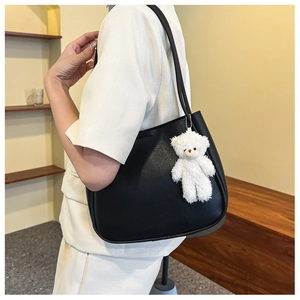 Détail d'un cabas en cuir noir mat avec un petit ours en peluche blanc sur le mannequin