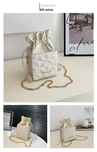 Detail of off-white bucket bag featuring geometric quilting and golden chain strap