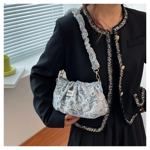 Detail of light blue floral pleated shoulder bag with texture and silver chain strap