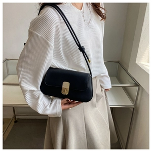 Close-up of a black leather shoulder bag featuring a vintage gold CD metal clasp and knot strap