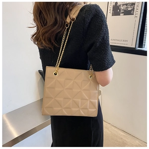 Modèle portant un sac beige à matelassage géométrique et bandoulière dorée