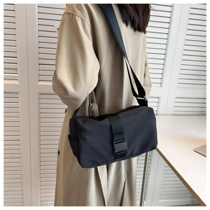 Detail of black crossbody bag with wide strap and plastic buckle on model