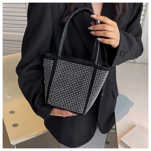 Detail of black bucket bag with silver rhinestone embellishments and leather handles