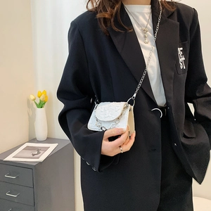 White floral lace micro crossbody bag with silver chain worn over a black blazer