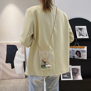Transparent PVC mini crossbody bag with gold chain strap shown on a green suit model