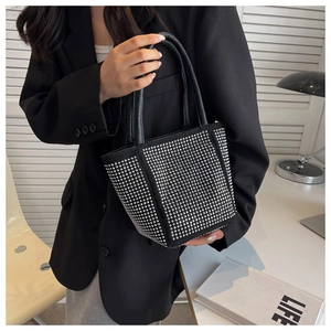 Close-up of black bucket bag with silver rhinestones and round handle in a modern setting