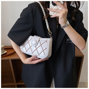 Close-up of a white quilted crossbody bag with brown stitching and large round buckle