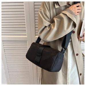 Detail of black waterproof nylon crossbody bag featuring horizontal buckle strap design