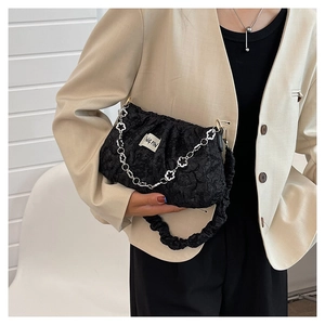 Detail view of black pleated cloud bag with elegant silver flower chain strap