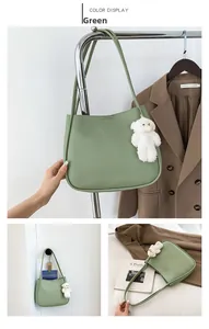 Détail du cabas en cuir vert pois avec breloque ours en peluche et doubles bandoulières