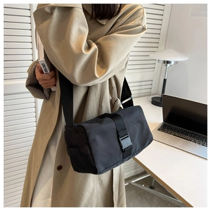 Detail of waterproof black nylon cylinder crossbody bag featuring durable industrial buckle