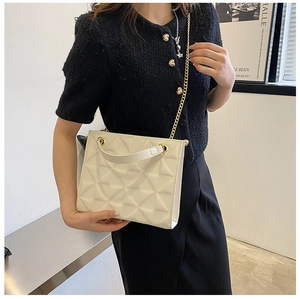 Détail du sac bandoulière crème avec texture 3D et chaîne dorée porté par le mannequin