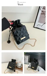 Detail of black quilted bucket bag with drawstring closure and golden metal chain strap