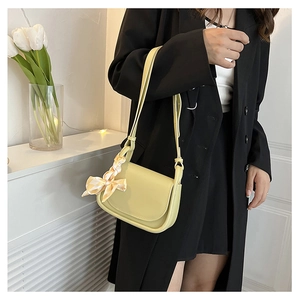 Dettaglio della borsa a tracolla giallo chiaro con foulard di seta vintage su sfondo floreale