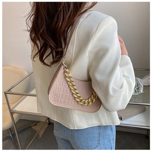 Detail of light pink crocodile pattern shoulder bag with chunky gold chain decoration