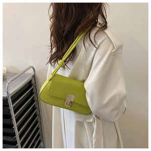 Green leather baguette bag with silver buckle and knot strap detail on white coat