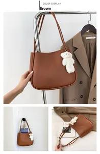 Détail d'un sac cabas en cuir marron avec un pendentif mignon d'ours en peluche blanc