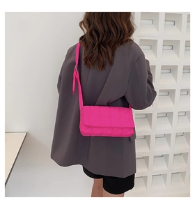 Hot pink quilted rectangular crossbody bag with adjustable wide strap on female model